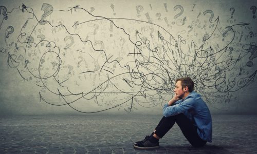 Molesto y cansado chico adolescente sentado en el suelo mantiene la mano en la mejilla mirando pensativo y sin esperanza. Estudiante estresado siente malestar emocional, ansiedad y problemas de salud mental.