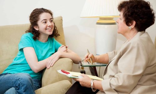 Woman interviewing a teen girl for college admission or job.  Could also be counseling session.