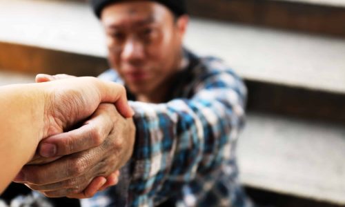 Handshake homeless man on walkway street in the city.