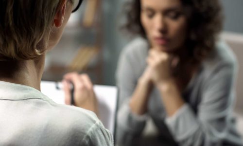 Young depressed woman talking to lady psychologist during session